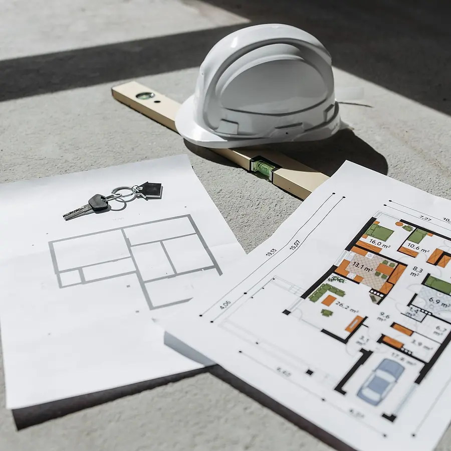 Printed floor plans with a set of keys and a safety helmet