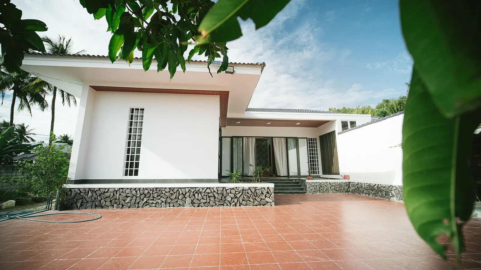 A white single-storey tropical house with a tiled terrace