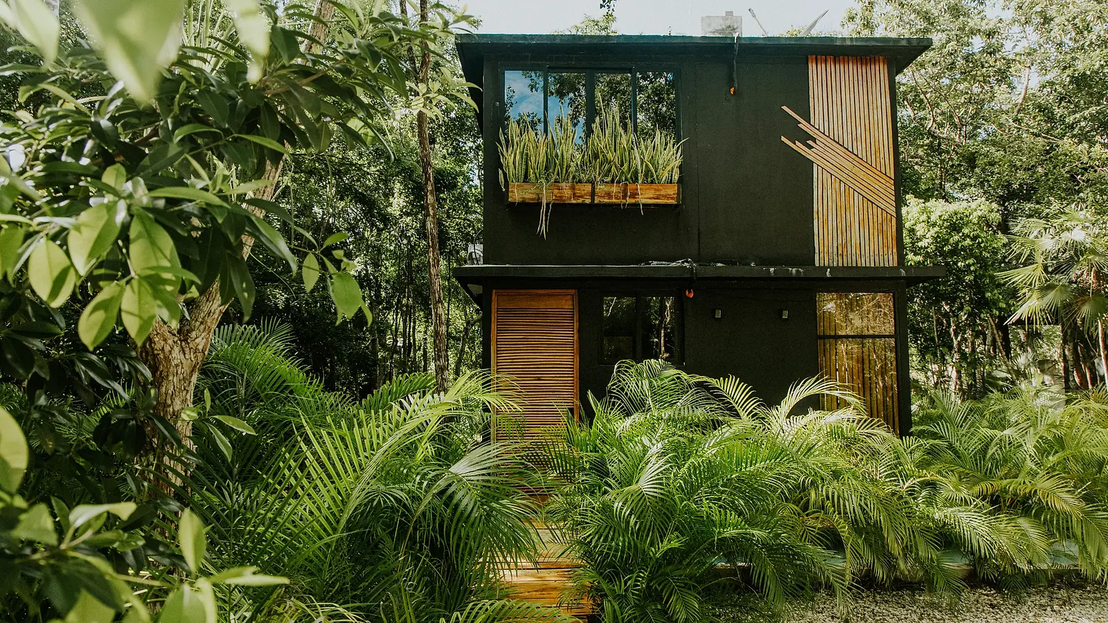 A two-storey house surrounded by tropical plants